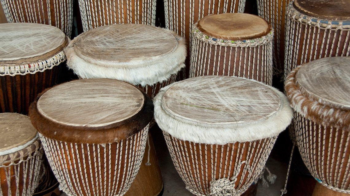 There are three drums of different sizes made of wood with animal skins across the tops.