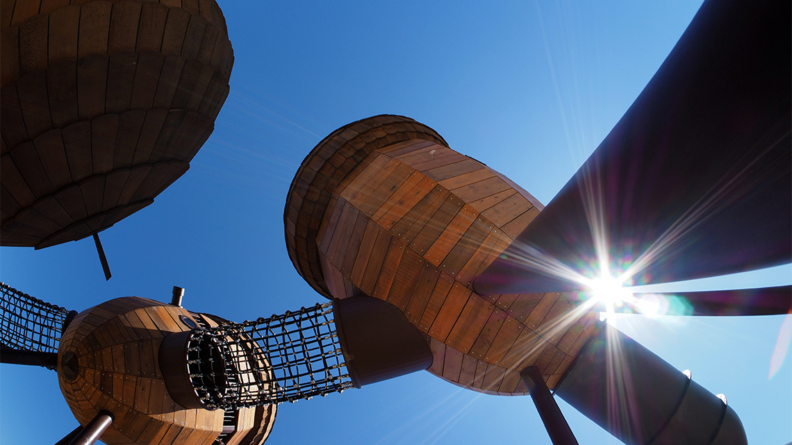 A playground with tall acorn-shaped buildings attached by net tunnels.