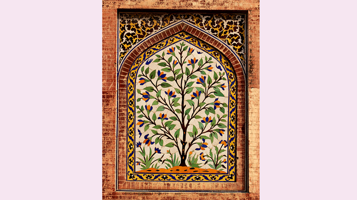 A wall with a painted tree. There are also decorated borders and brick in a door shape.