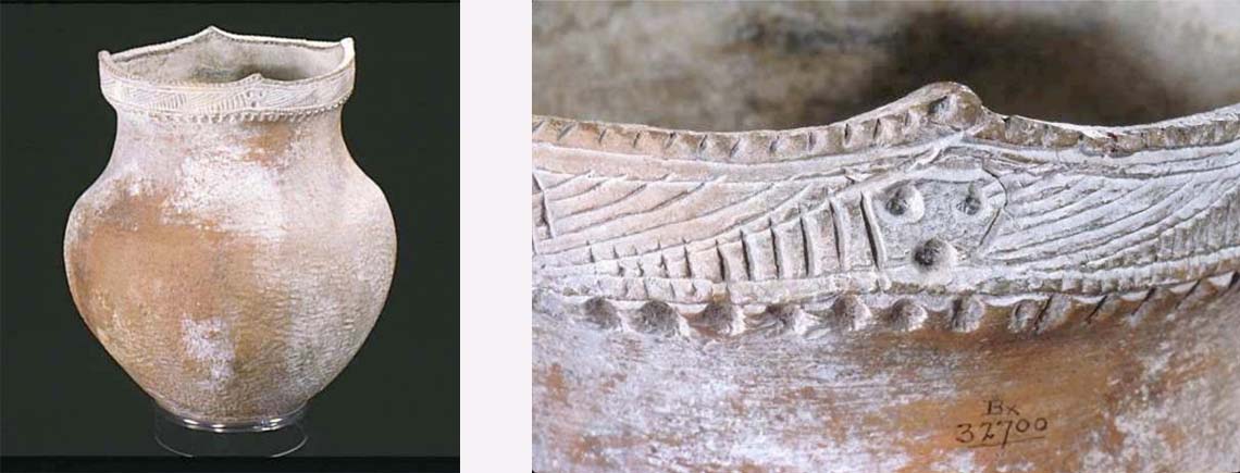 A clay pot with a skinny base, wide middle, and less wide rim at the top. The rim has decorative lines and dots.
