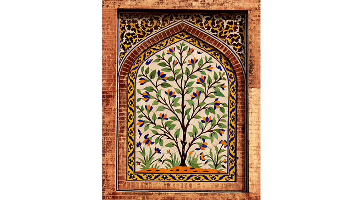 A wall with a painted tree. There are also decorated borders and brick in a door shape.