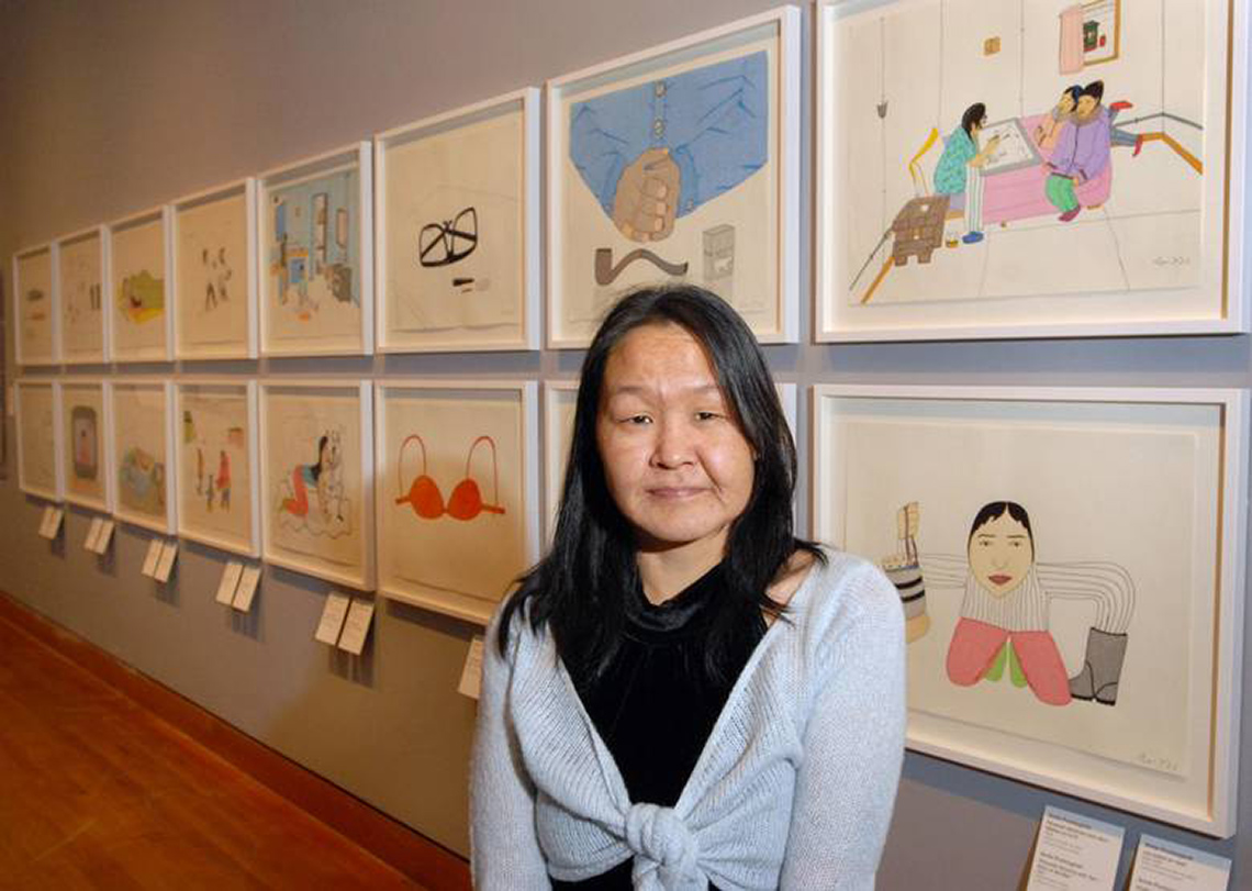 Annie Pootoogook A photograph of the artist Annie Pootoogook in front of her artwork.