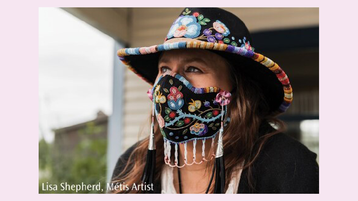 A person wearing a mask and hat that has colourful beaded floral patterns on black fabric.