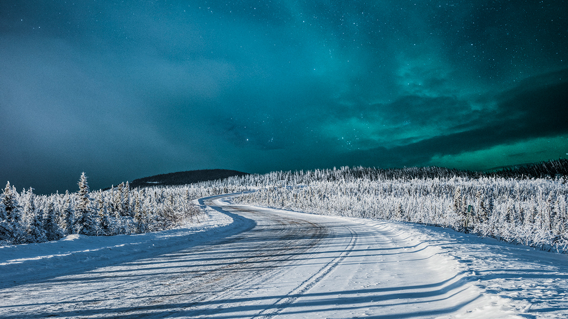 Northern lights over a snow-covered road 