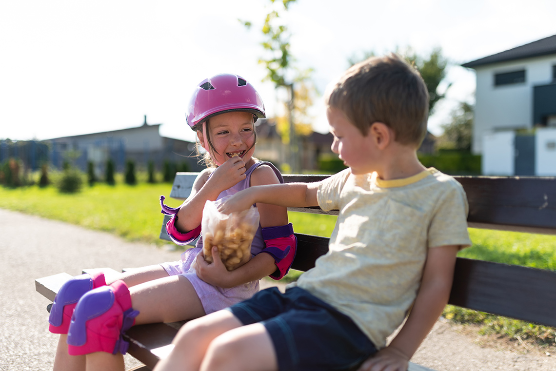 Connecting through kindness Two children sitting on a bench sharing a snack