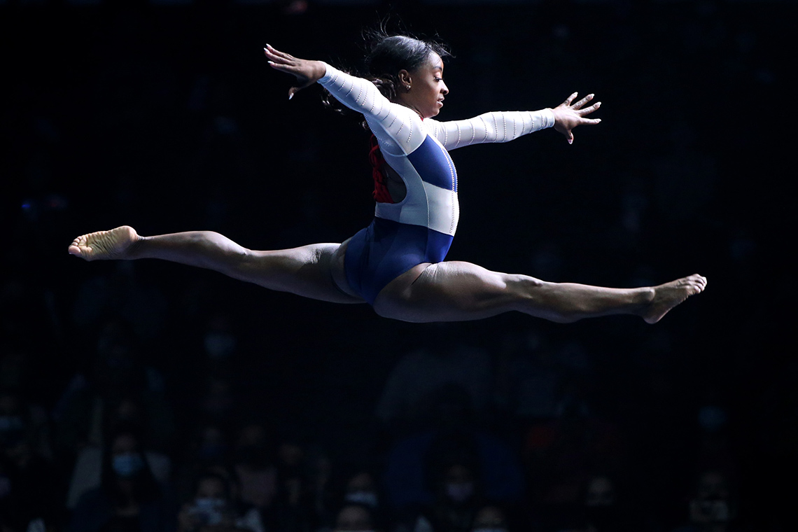 A gymnast performing; their hands and legs are stretched mid-air.