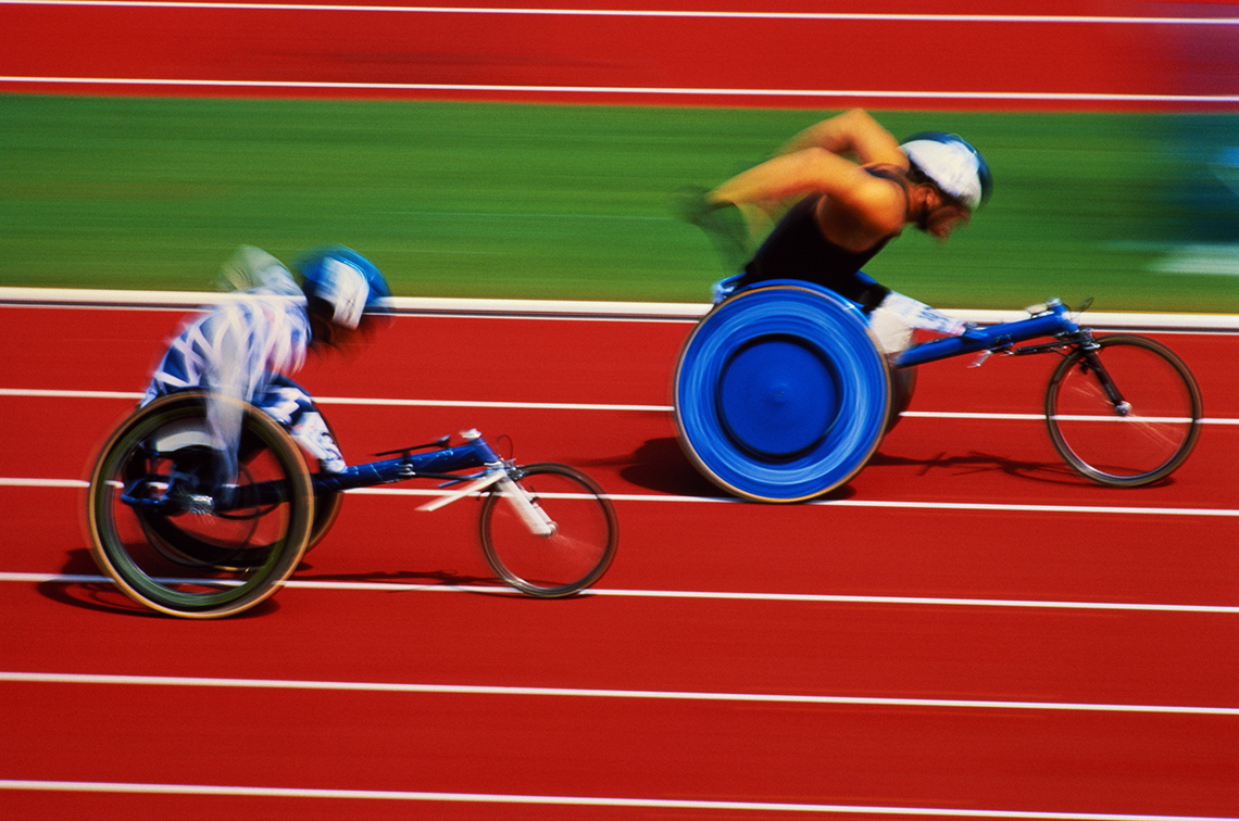 Two athletes in action at a wheelchair racing track.
