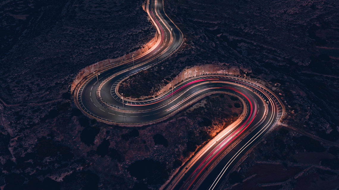 A road that begins with a slight curve, then curves tightly in the middle section, and then moves back out to a slight curve at the end.