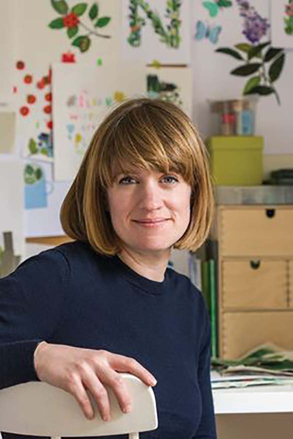 Clover Robin sitting in front of collages in her studio.