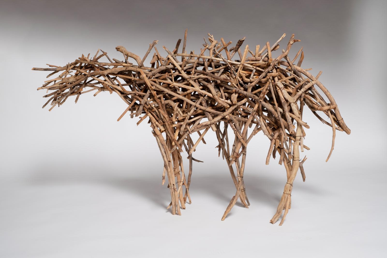 The figure of a horse made out of many large sticks held together with wire.
