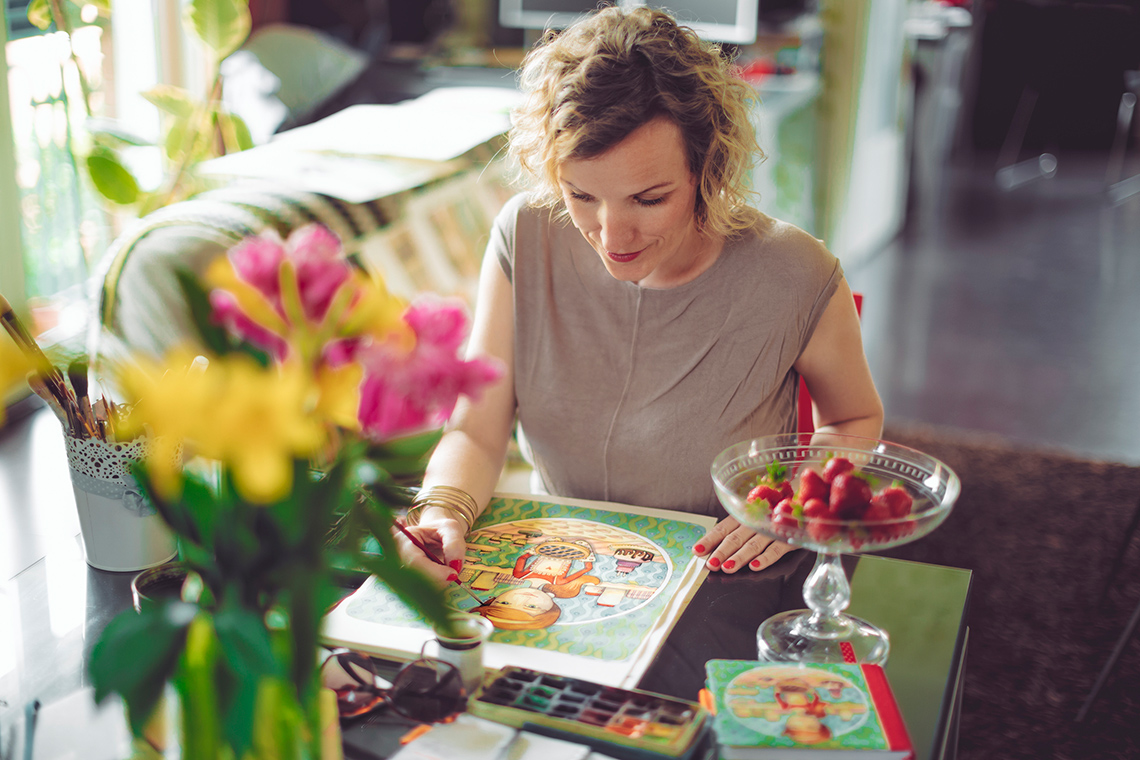An illustrator paints the cover of a children's book.