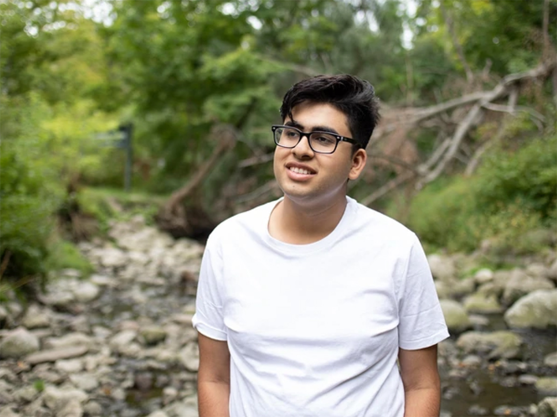 A smiling young man in a natural setting