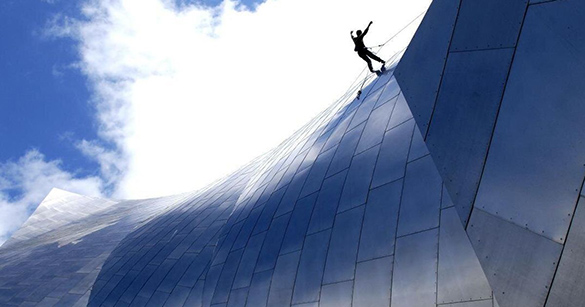 A dancer performing a piece suspended on the outside of a tall building.