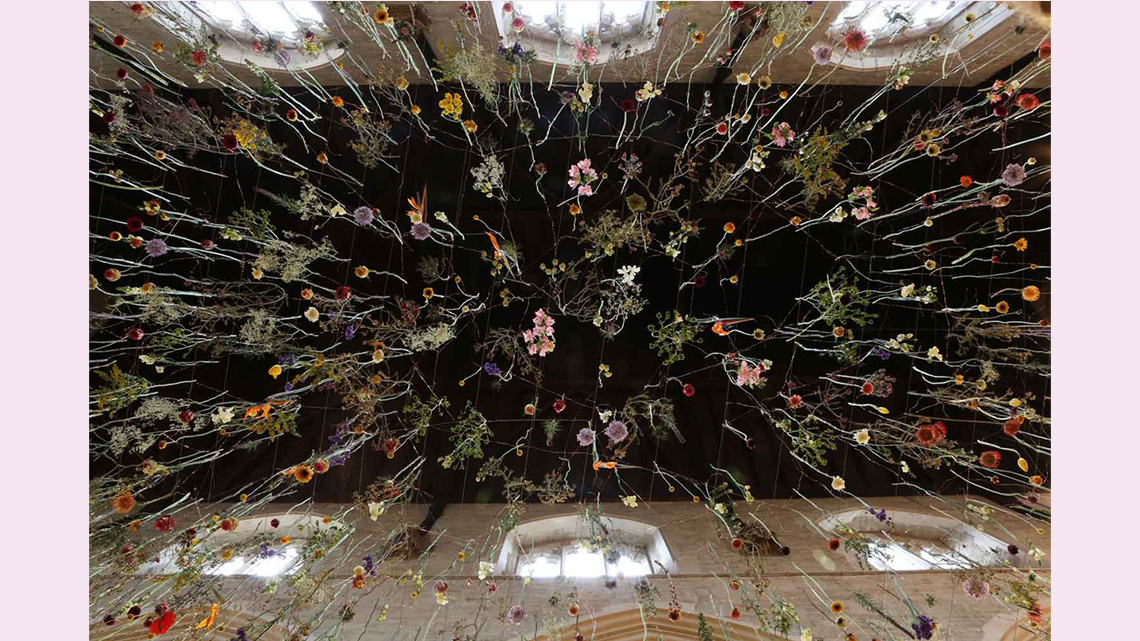 A huge number of flowers hanging from a ceiling. The image is photographed from underneath the flowers.