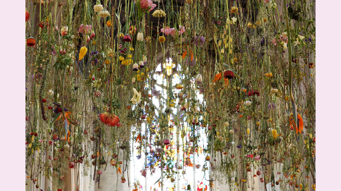 A huge number of flowers hanging from a ceiling. The image is photographed through the flowers.