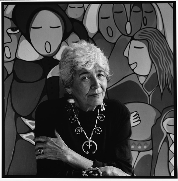 A photo of Daphne Odjig in front of one of her large artworks.
