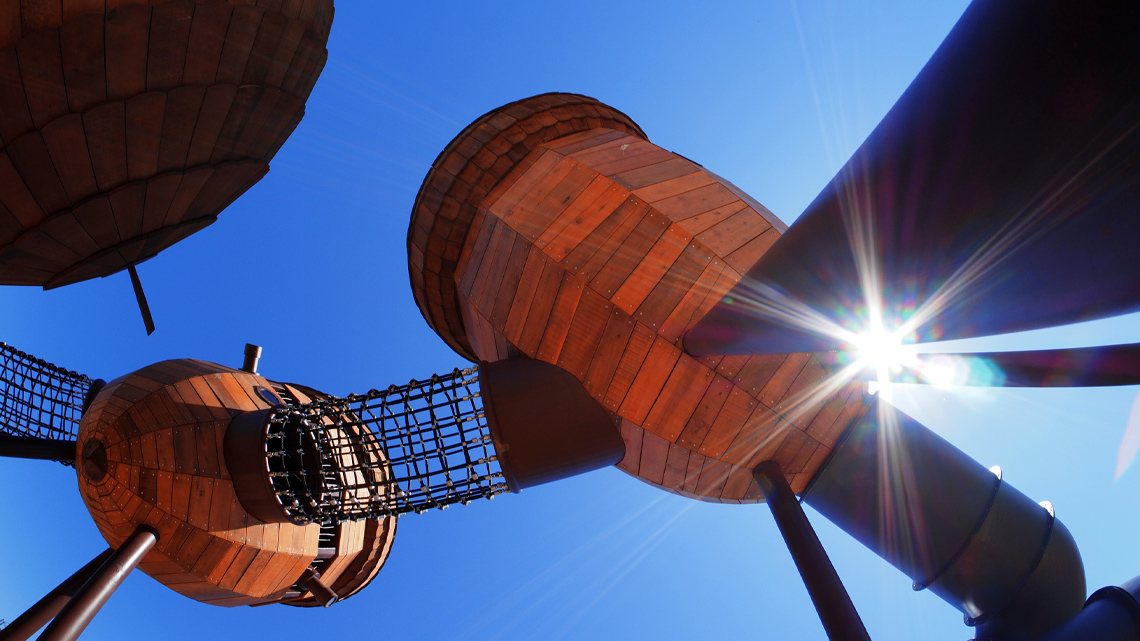 A playground with tall acorn-shaped buildings attached by net tunnels.