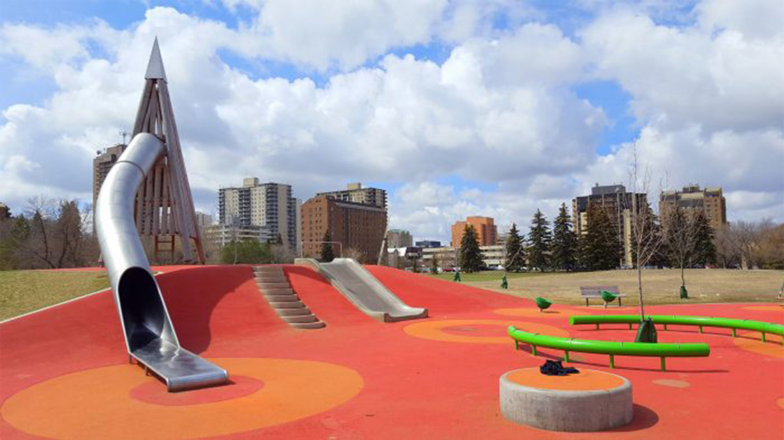 A playground is built into a hill with slides, stairs, and balance beams.