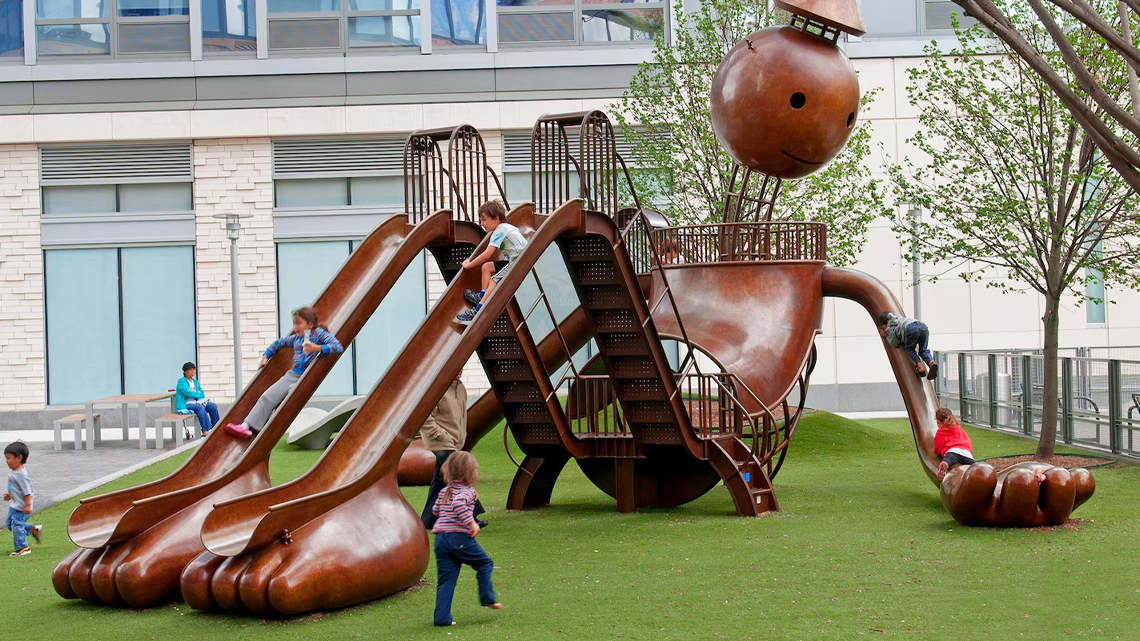 Bronze structure of a giant allows children to climb the limbs, look through the eyes, and slide down the legs.