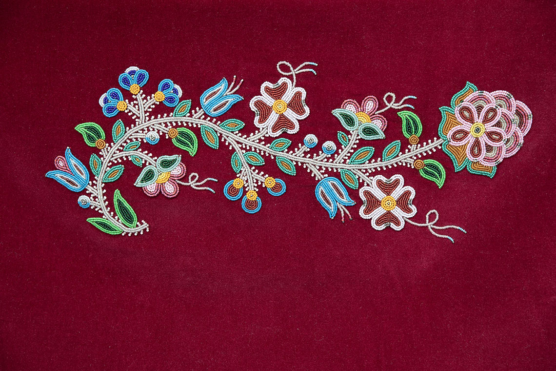 A beadwork art piece with multiple kinds of flowers on a beaded vine, created by Metis artist Jennine Krauchi