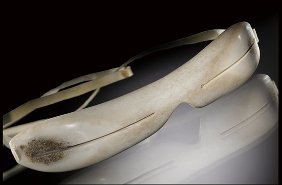 Snow goggles made with carved caribou bone and with a caribou strap. Narrow slits are carved through the bone on each side of the goggles.