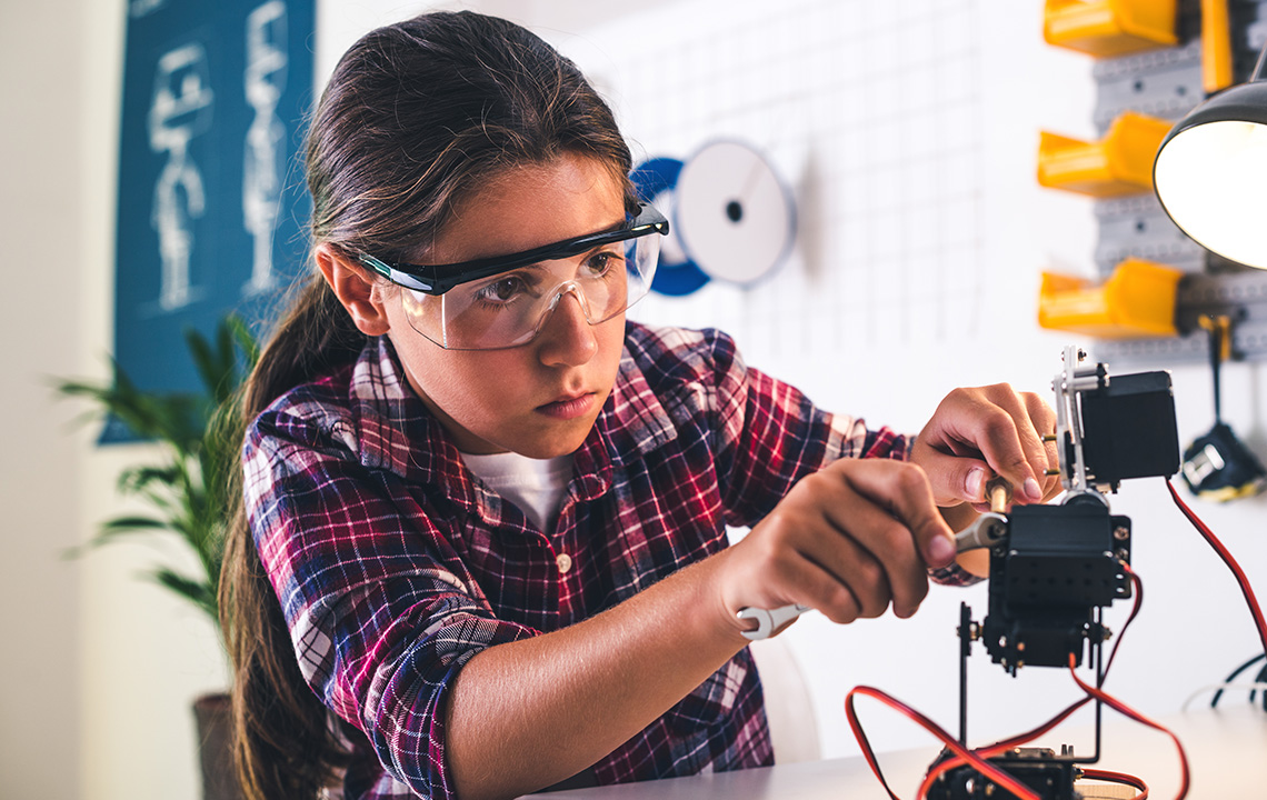 A student in a robotics lab working on a robot arm model.