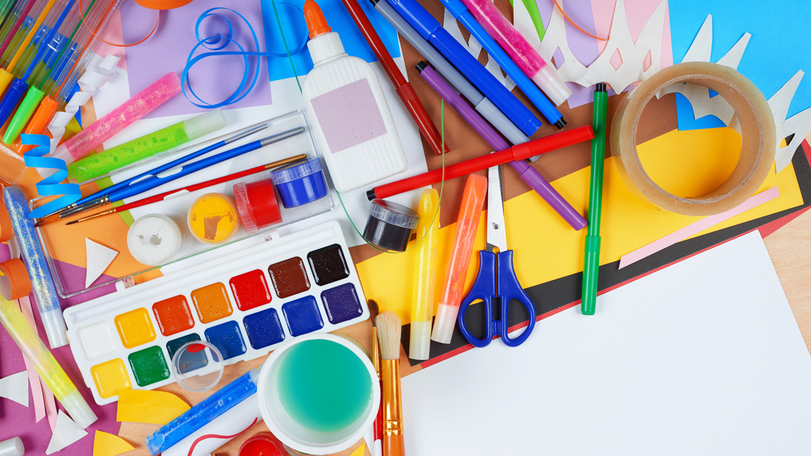 Arts and craft supplies, including tape, glitter glue, scissors, markers, and construction paper.