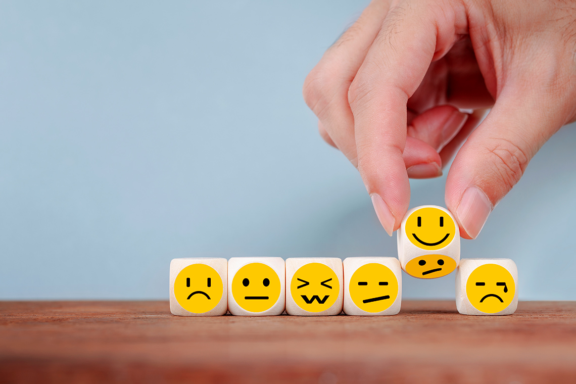 Six dice, each with an emoji of a different emotion: sad, neutral, surprised, unimpressed, happy, and upset.