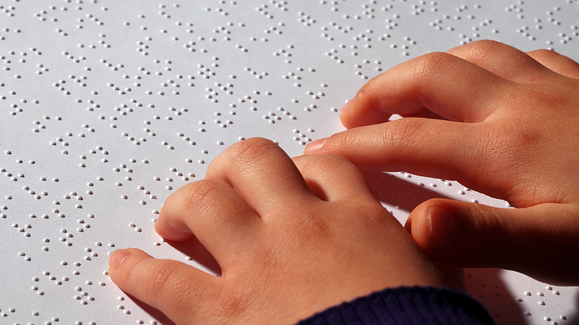 A sheet of Braille paper embossed with raised dots for a visually impaired reader.