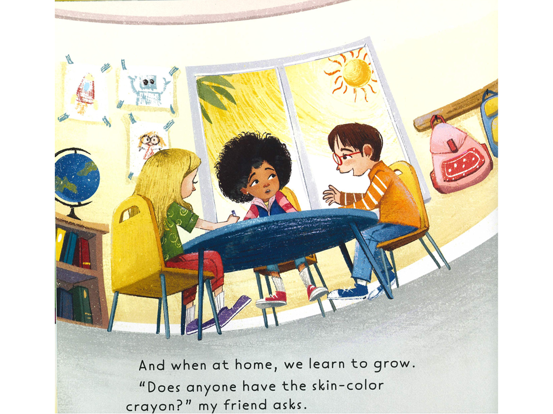 An indoor classroom scene with three children seated around a small, round table engaged in conversation as they draw and colour. Behind them, a large window shows a bright yellow sun and to the left of the window, taped drawings display various colorful images.