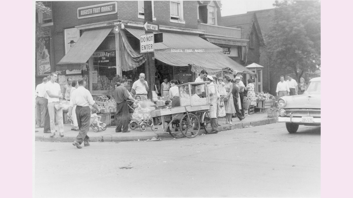 A lively open-air fruit and vegetable market on a city street.