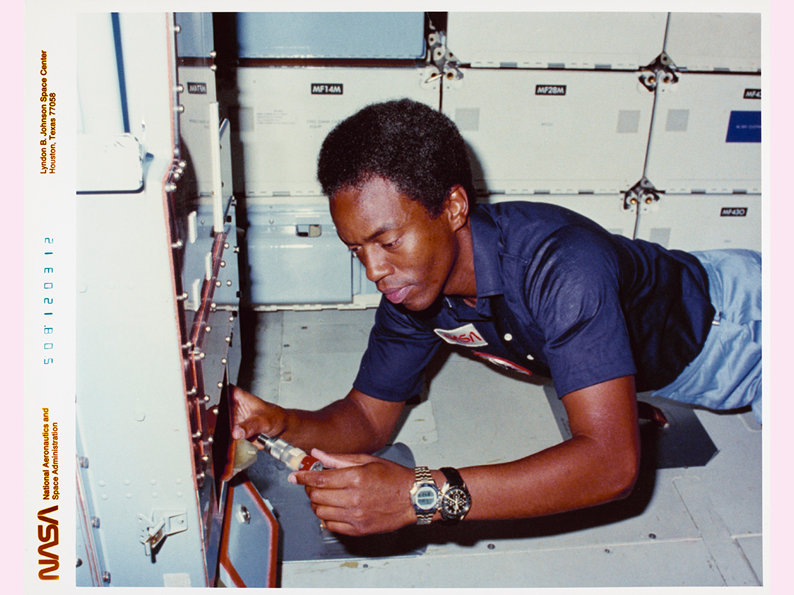A Black male NASA astronaut working in a spacecraft.