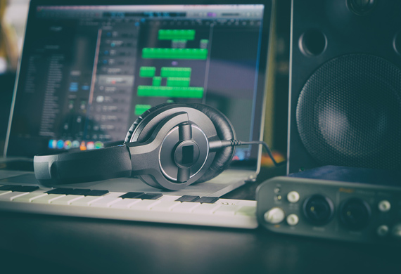 A computer connected to a musical keyboard, an audio interface, headphones, and speakers