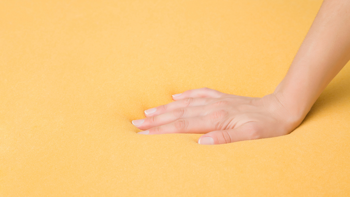A hand pressing down into memory foam