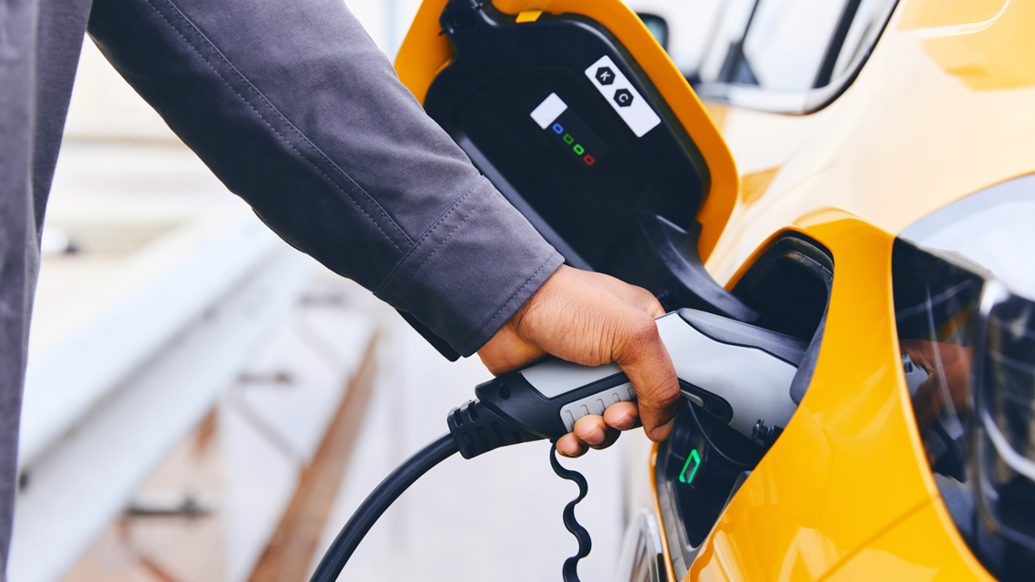 Person connecting their electrical car to a source of electricity.