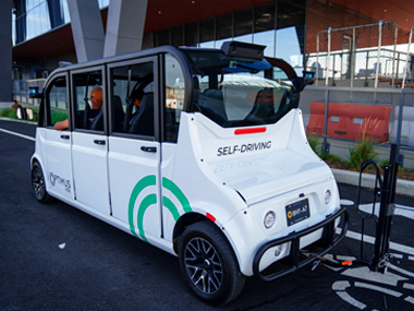 An autonomous six-seater shuttle bus from Optimus Ride is driving on a road.