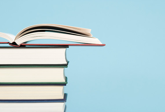 A stack of books with an open book on top.