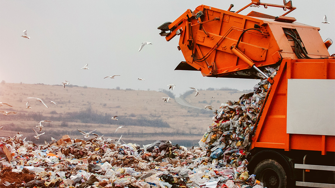 A garbage truck emptying its trash at a landfill.