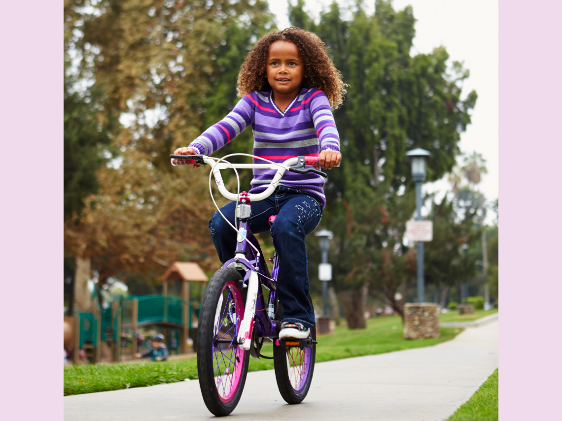 A young girl rides her bike in a park.