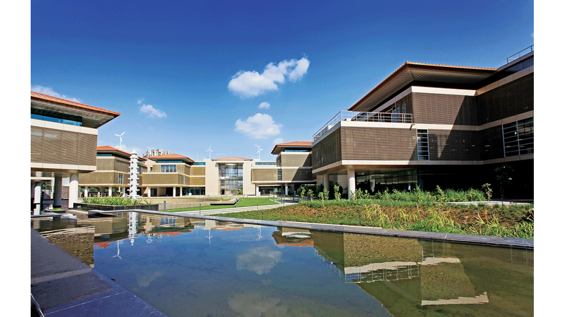 A series of two storey buildings built along a water features and pathways between plants.