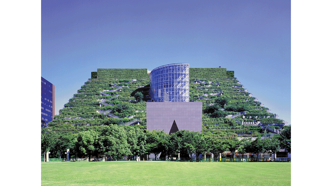 A multi-storey building covered in greenery, with a large glass section throughout the middle.