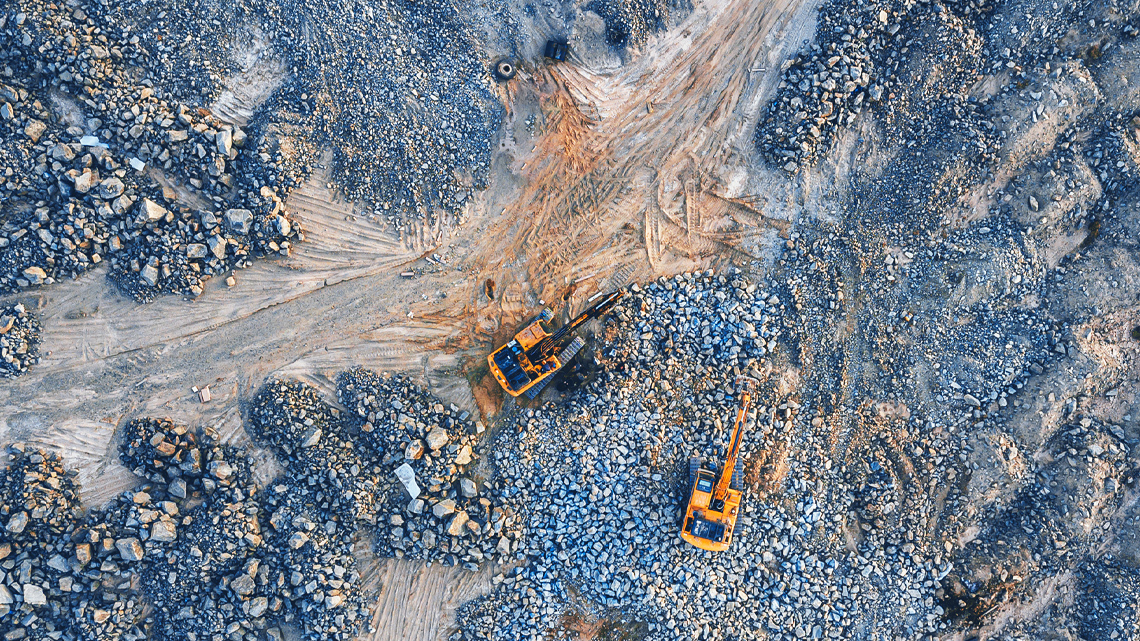 A mined area of land with two excavator construction vehicles digging.
