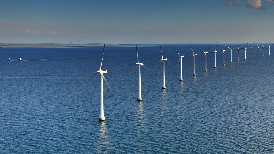Open water with a line of offshore wind turbines.