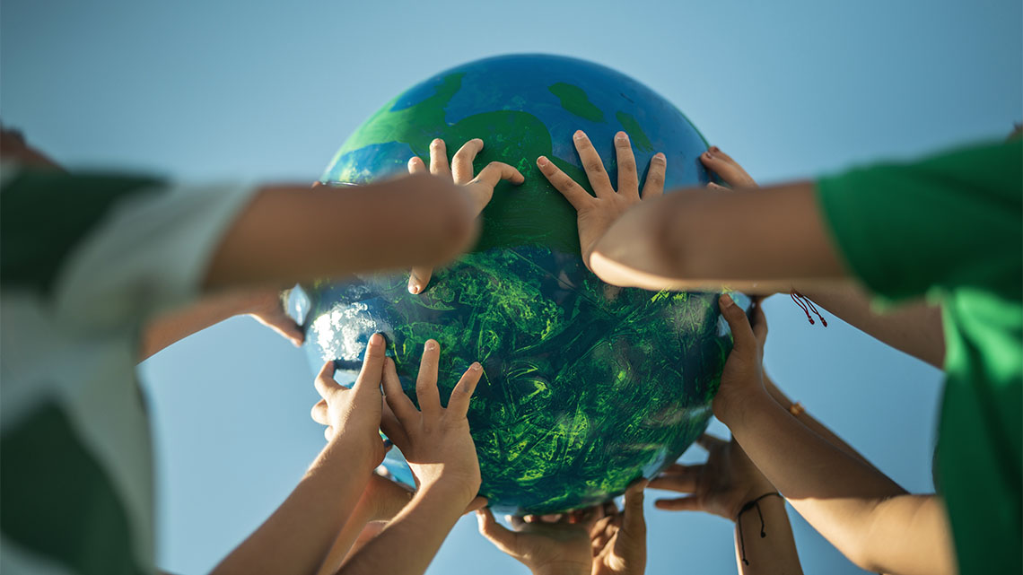 Several hands holding up a globe.