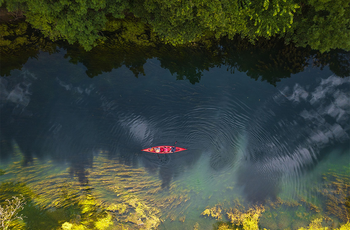 Looking down on a lake with a canoe in the middle.
