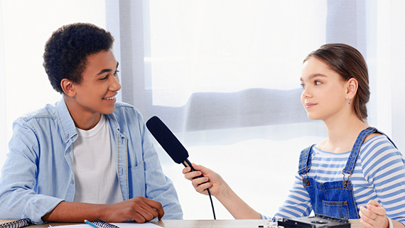 Two students recording audio using a microphone.
