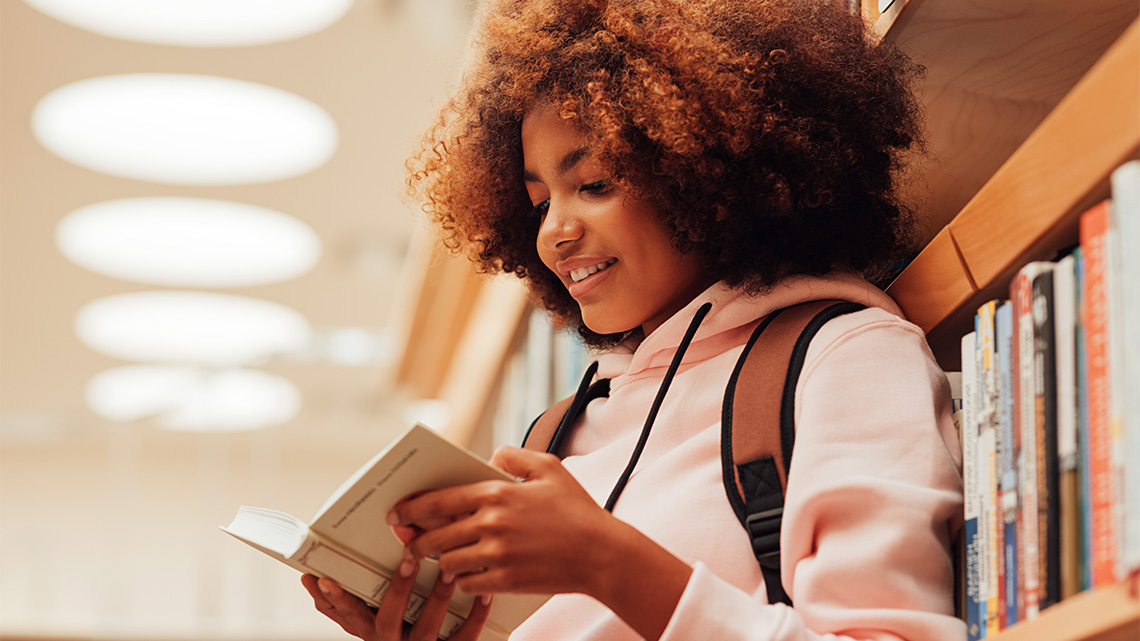 A student reading a book in the library.
