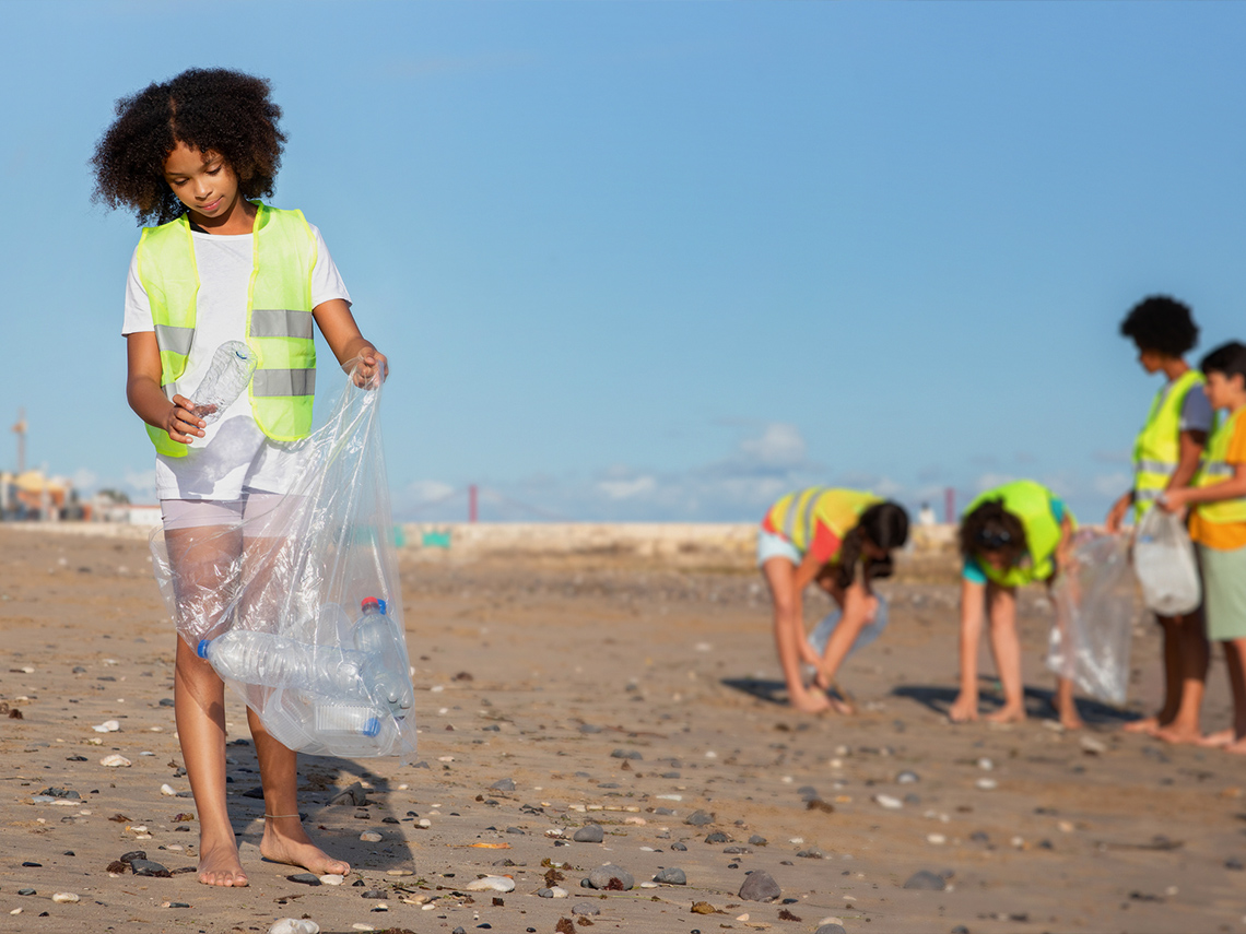 Teens cleaning up trash on the beach.