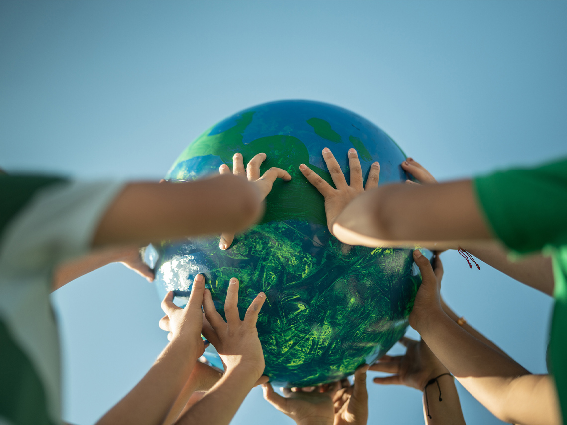 Many hands holding up a globe.