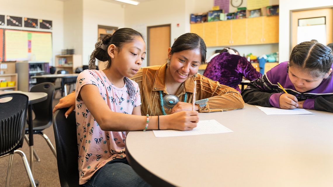 A teacher works with students at their desks.